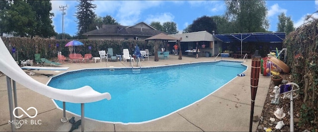 view of swimming pool featuring a diving board, a patio area, and a water slide