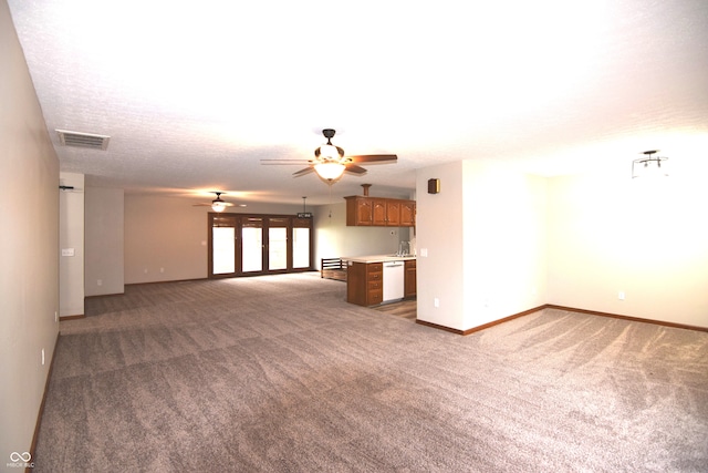 unfurnished living room featuring ceiling fan, a textured ceiling, and dark colored carpet