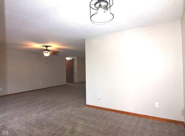 carpeted empty room featuring a barn door, ceiling fan, and a textured ceiling