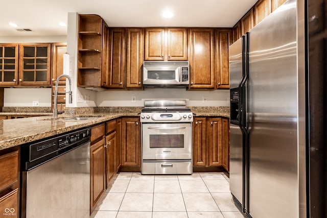 kitchen with light tile patterned flooring, stone countertops, sink, and stainless steel appliances