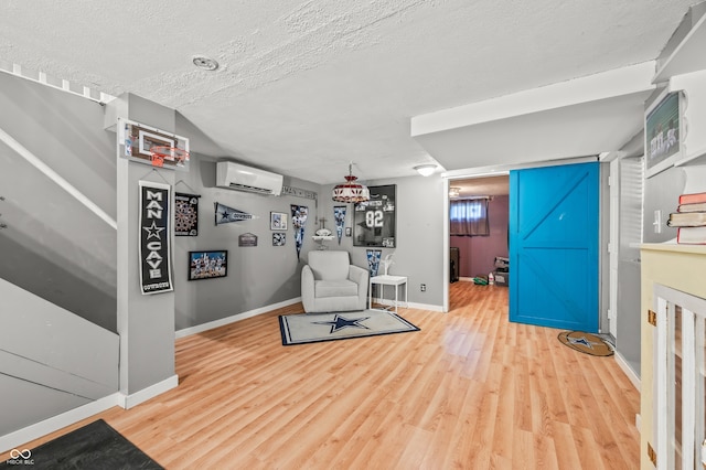 living room featuring wood-type flooring, a textured ceiling, and a wall mounted AC