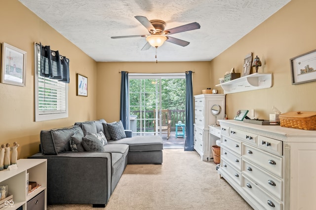 living room with a textured ceiling, ceiling fan, and light colored carpet