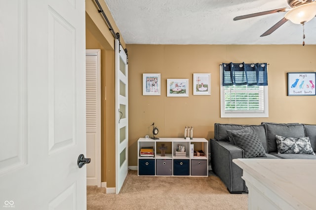 carpeted bedroom featuring ceiling fan, a textured ceiling, and a barn door