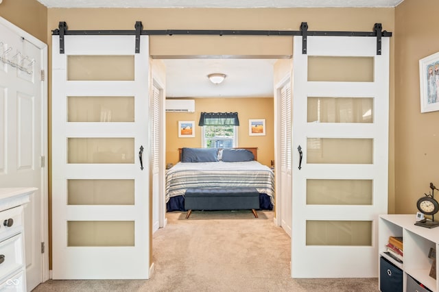 bedroom with a barn door, light colored carpet, and an AC wall unit