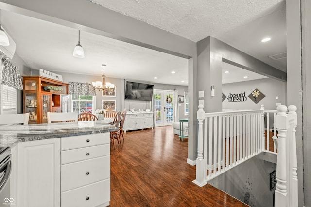 kitchen with white cabinetry, light stone countertops, a textured ceiling, dark hardwood / wood-style flooring, and a notable chandelier