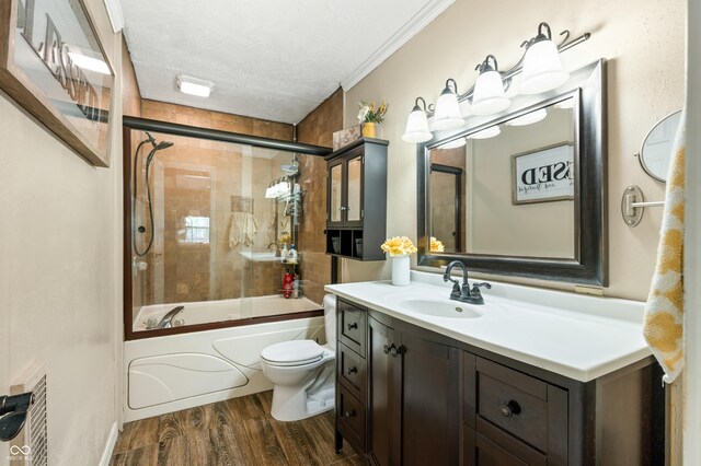 full bathroom with hardwood / wood-style flooring, a textured ceiling, vanity, crown molding, and toilet