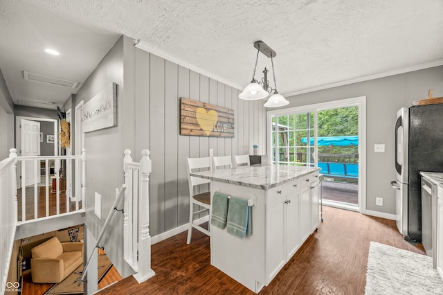 kitchen with dark hardwood / wood-style floors, a kitchen island, hanging light fixtures, stainless steel refrigerator, and white cabinetry