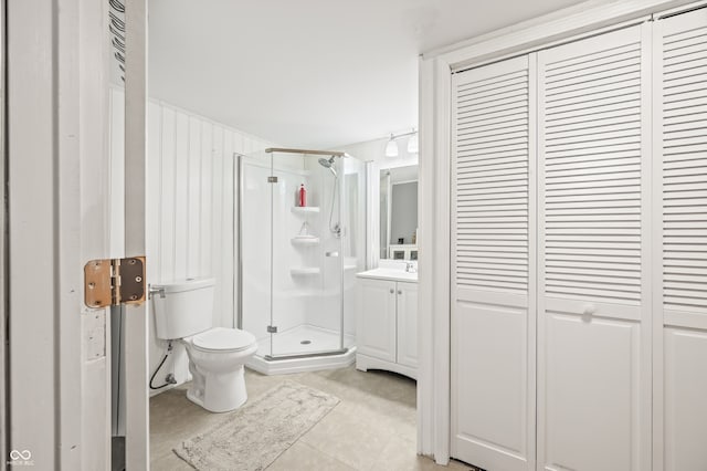 bathroom featuring tile patterned flooring, toilet, a shower with shower door, and vanity