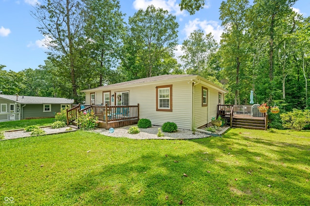 rear view of house with a wooden deck and a lawn