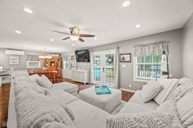 living room featuring hardwood / wood-style floors, ceiling fan with notable chandelier, french doors, and an AC wall unit