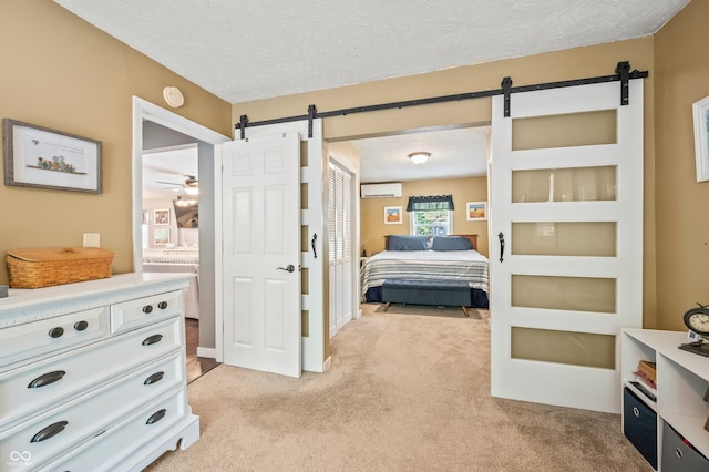 carpeted bedroom featuring a wall mounted AC, a textured ceiling, and a barn door