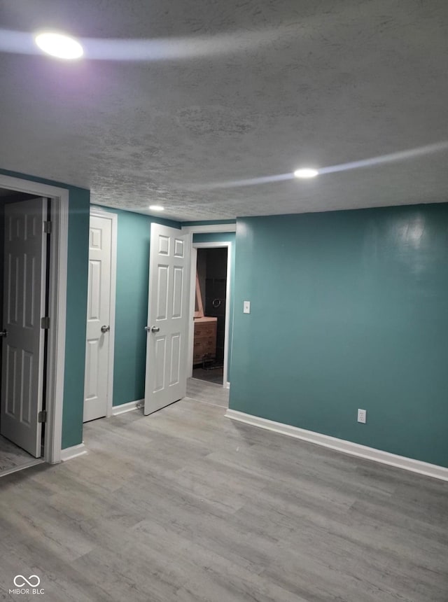 basement with hardwood / wood-style floors and a textured ceiling