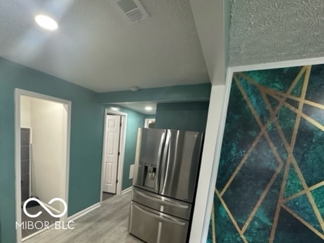 kitchen featuring wood-type flooring and stainless steel refrigerator with ice dispenser