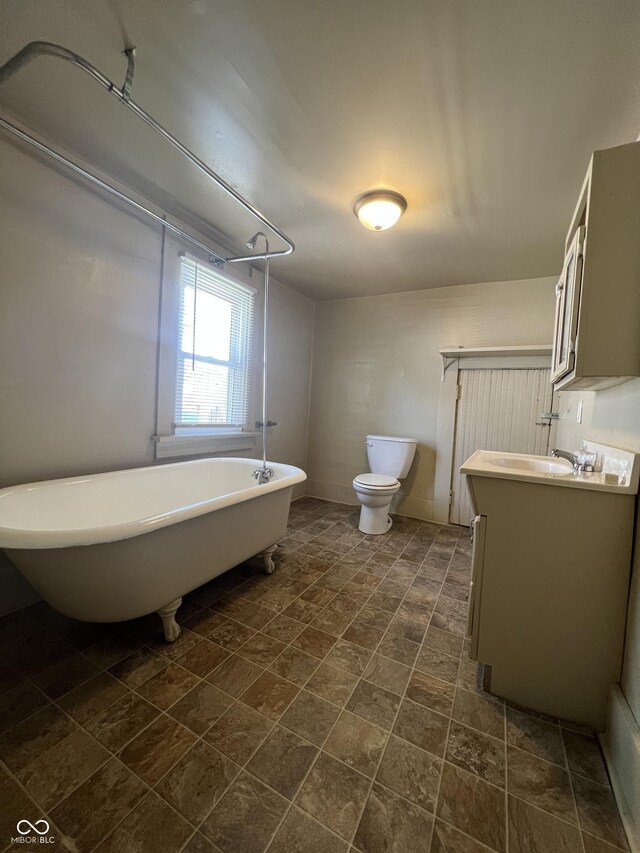 bathroom with a washtub, vanity, and toilet