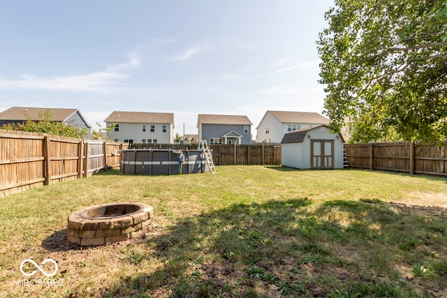 view of yard featuring a storage unit, a fire pit, and a fenced in pool