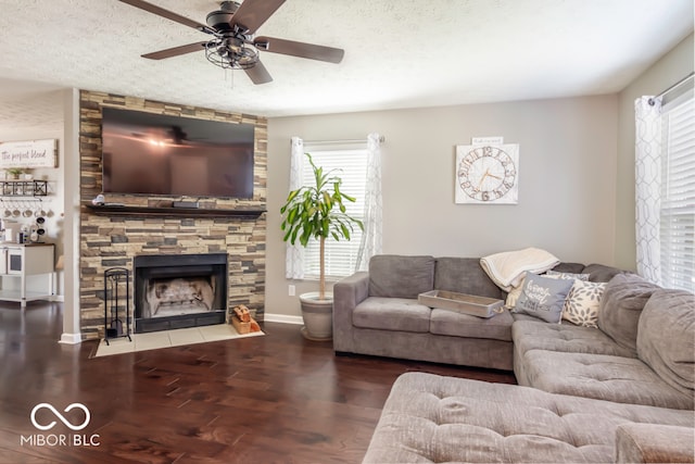 living room featuring ceiling fan, wood-type flooring, a textured ceiling, and a fireplace