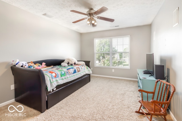 bedroom with ceiling fan, light carpet, and a textured ceiling