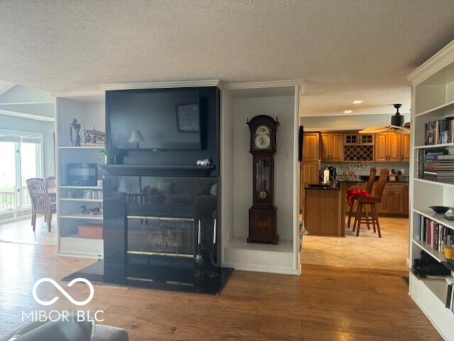 living room featuring a textured ceiling, ceiling fan, and wood-type flooring