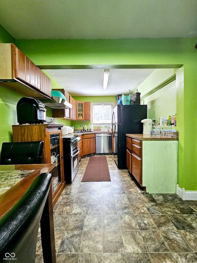 kitchen featuring wall chimney range hood, tile patterned floors, sink, and appliances with stainless steel finishes