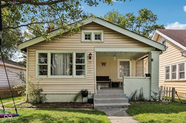 bungalow-style house featuring covered porch, a chimney, and fence