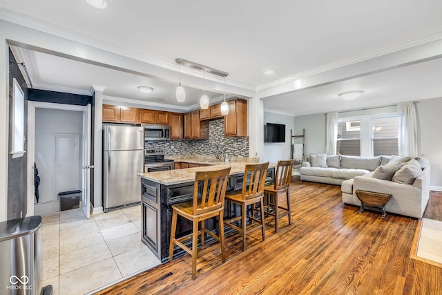 kitchen with light hardwood / wood-style flooring, tasteful backsplash, appliances with stainless steel finishes, decorative light fixtures, and crown molding