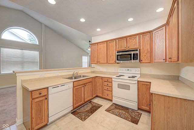 kitchen featuring vaulted ceiling, white appliances, kitchen peninsula, sink, and light tile patterned flooring