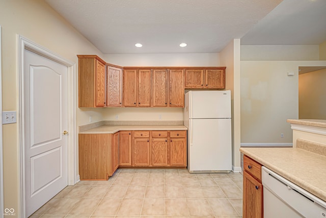 kitchen featuring a textured ceiling, light tile patterned floors, and white appliances