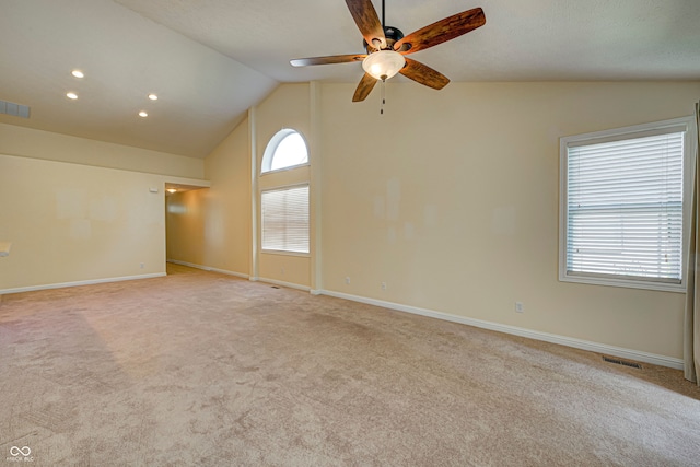 empty room featuring a healthy amount of sunlight, ceiling fan, light carpet, and vaulted ceiling