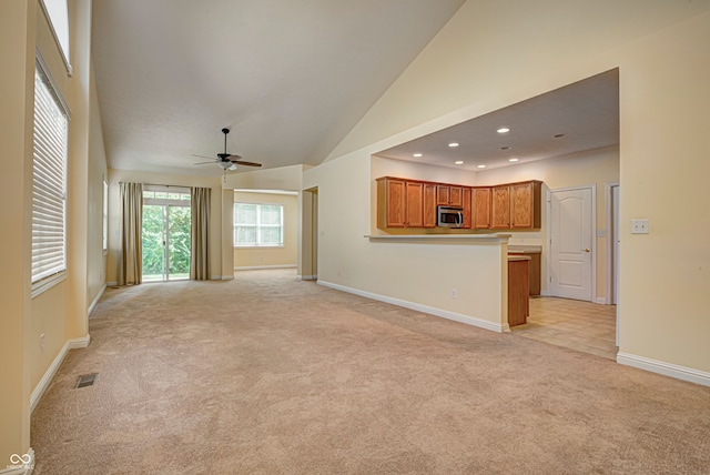 unfurnished living room featuring high vaulted ceiling, ceiling fan, and light carpet