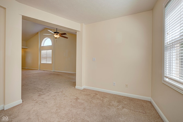 unfurnished room featuring light colored carpet, lofted ceiling, ceiling fan, and a textured ceiling