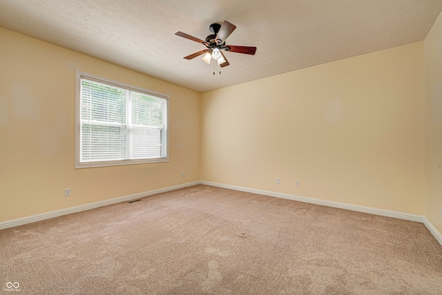 spare room featuring ceiling fan, light colored carpet, and a textured ceiling