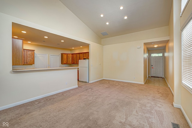 unfurnished living room featuring light carpet and high vaulted ceiling