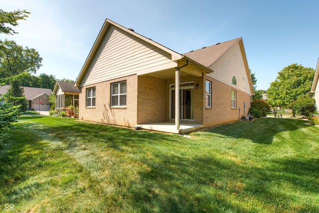 rear view of house with a lawn and a patio