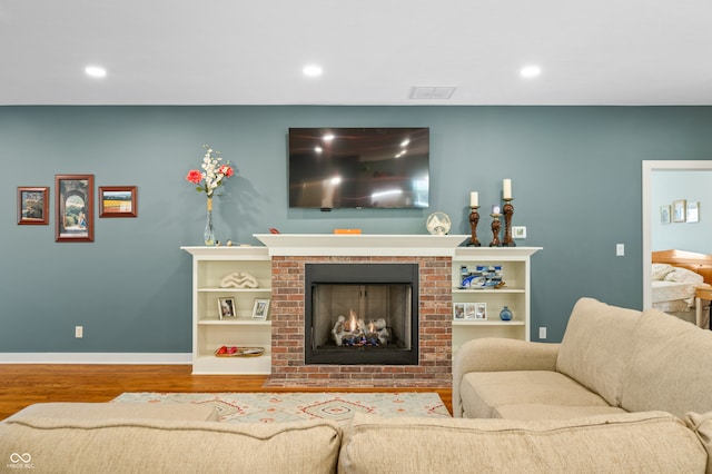 living room featuring wood-type flooring and a brick fireplace