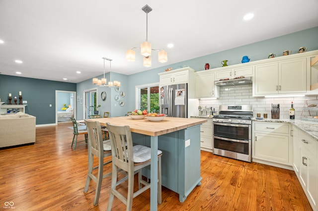 kitchen featuring light hardwood / wood-style flooring, stainless steel appliances, an inviting chandelier, and butcher block countertops