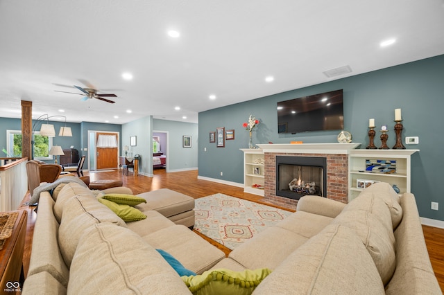 living room with a fireplace, light hardwood / wood-style flooring, and ceiling fan