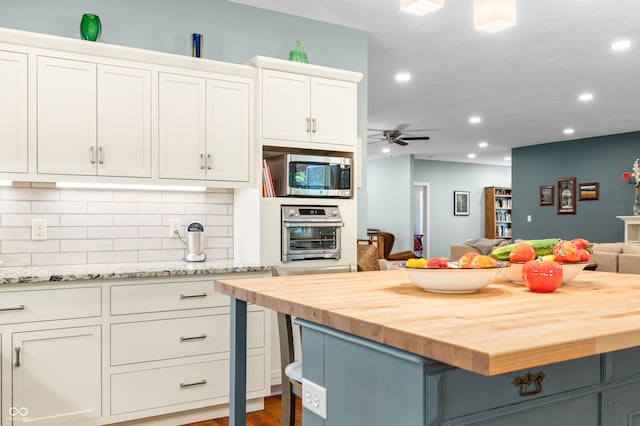 kitchen featuring white cabinetry, butcher block counters, a kitchen island, ceiling fan, and appliances with stainless steel finishes