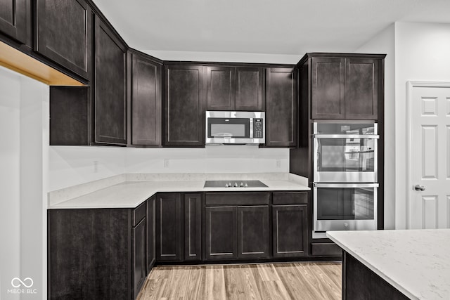 kitchen featuring dark brown cabinets, stainless steel appliances, and light hardwood / wood-style floors