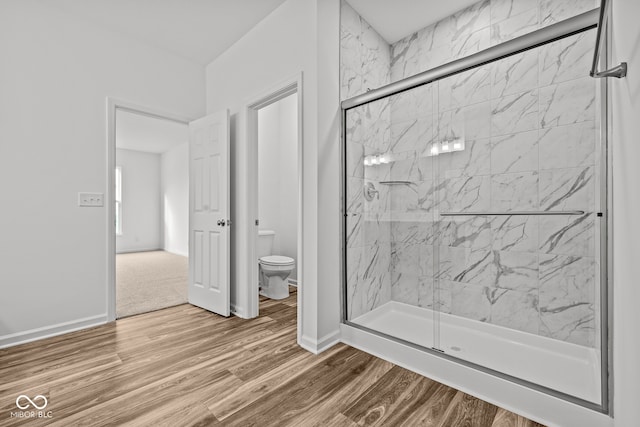 bathroom with wood-type flooring, walk in shower, and toilet