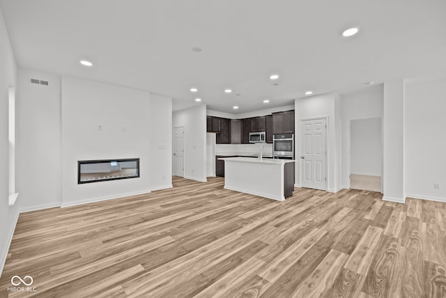 unfurnished living room with light wood-type flooring and sink