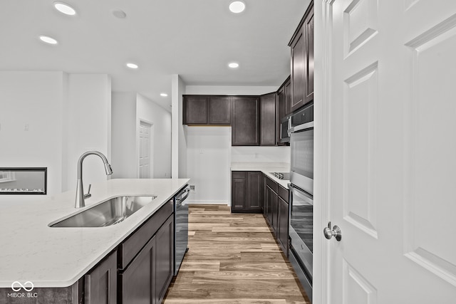 kitchen with dark brown cabinetry, light stone counters, sink, wood-type flooring, and dishwasher