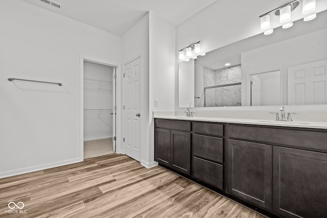 bathroom with hardwood / wood-style floors, a shower with shower door, and vanity