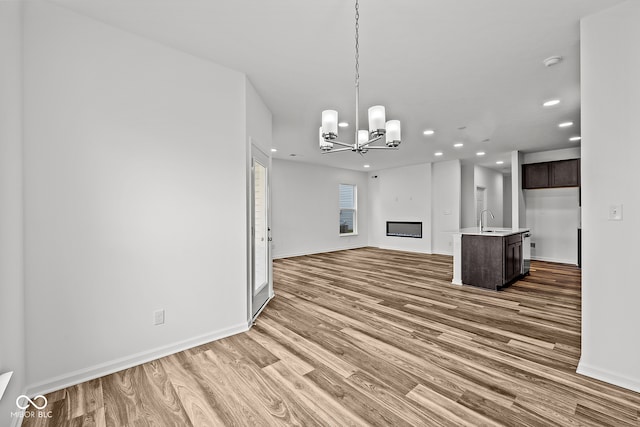 unfurnished living room featuring wood-type flooring, a chandelier, and sink