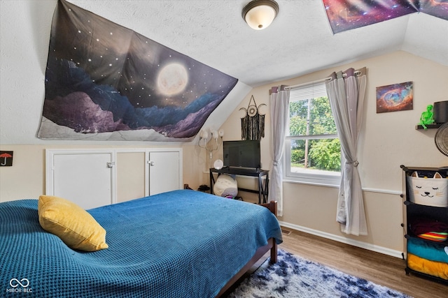 bedroom featuring lofted ceiling, hardwood / wood-style flooring, and a textured ceiling