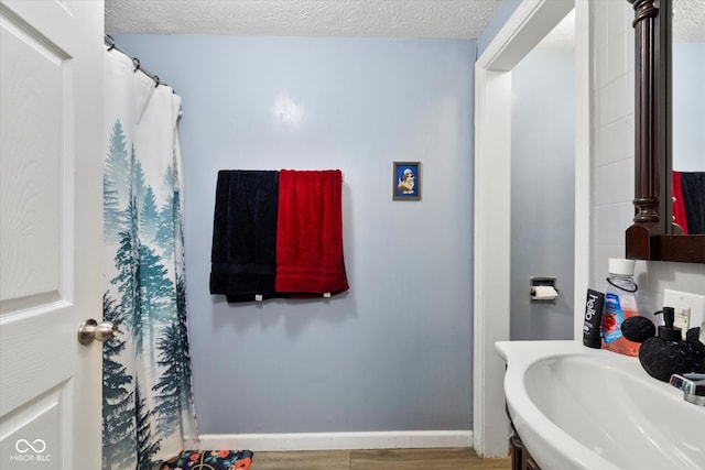 bathroom featuring wood-type flooring, sink, and a textured ceiling