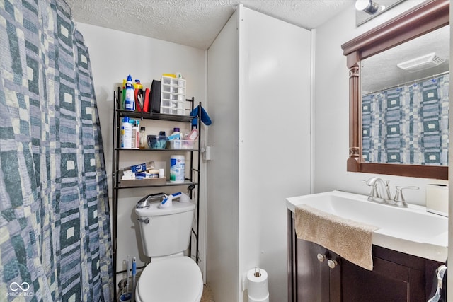 bathroom with a textured ceiling, vanity, and toilet