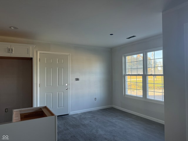 unfurnished room with dark colored carpet and ornamental molding