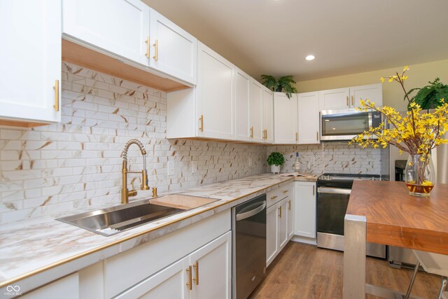 kitchen with white cabinets, sink, dark hardwood / wood-style floors, decorative backsplash, and appliances with stainless steel finishes