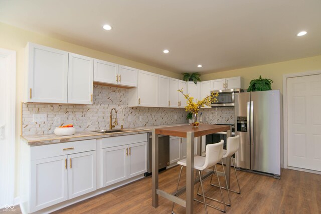 kitchen with white cabinets, sink, appliances with stainless steel finishes, and hardwood / wood-style floors