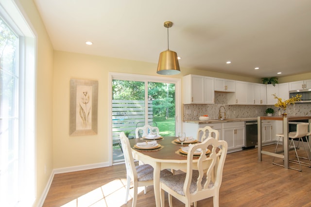 dining area featuring light wood-type flooring, wine cooler, plenty of natural light, and sink